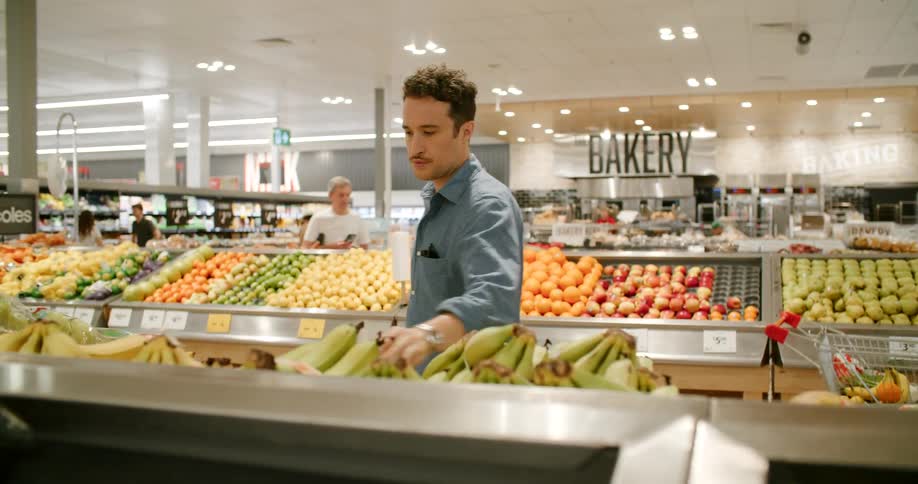 A man picking out bananas in the produce section of a grocery store