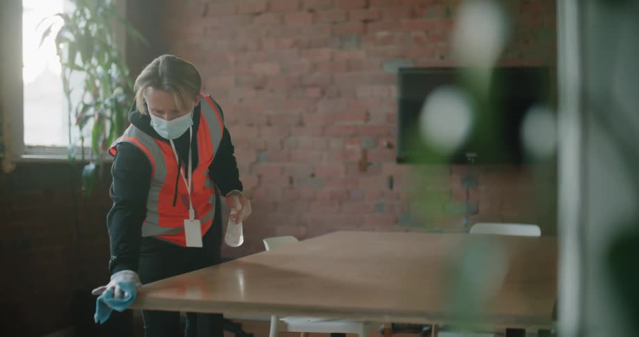 A man is spraying the table and wiping it with a rag