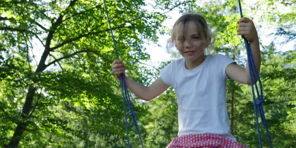 A young girl playing on a rope swing on a summer day