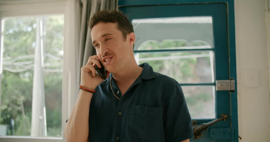 A man stands at home and talks on a cell phone