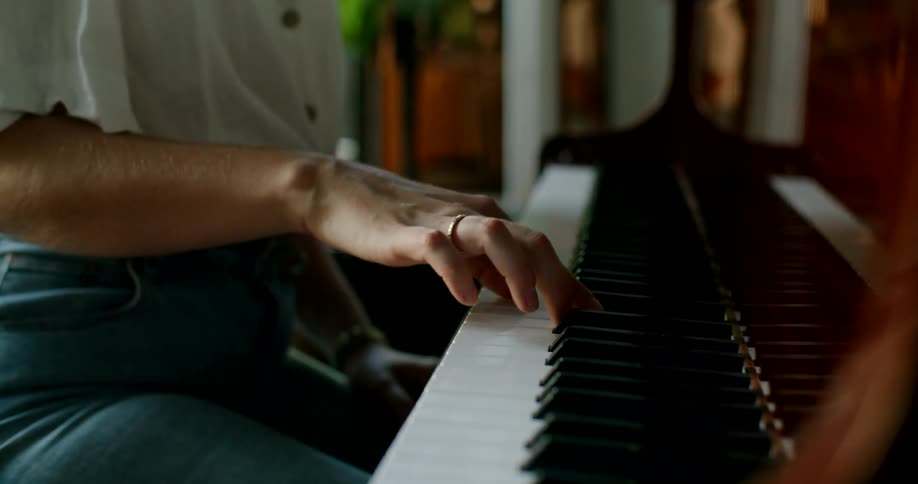 A person with a ring in a room sitting at a piano and playing