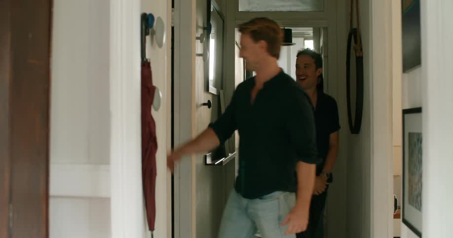 Three people walk down the hall talking