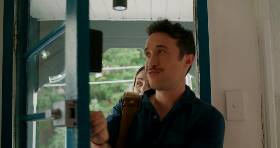 A woman is excited as her boyfriend unlocks the front door to a cottage and they walk inside