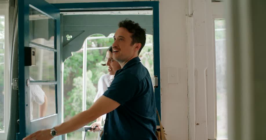 A man and a woman with luggage opening a door and entering into a house