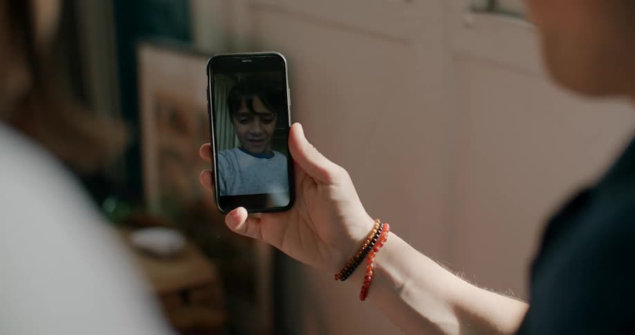 A person in a room holding a smart phone and video chatting with another person