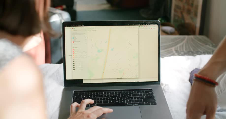 A couple uses a laptop to search an address on a map app at home