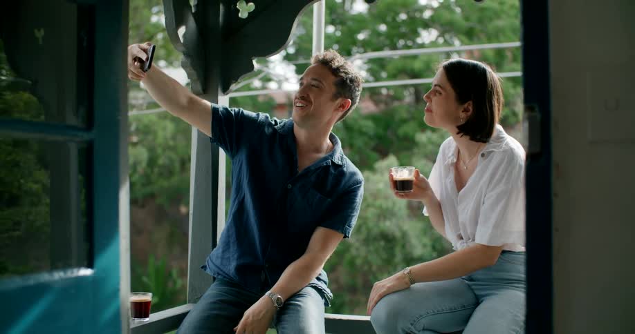 A man poses with a woman as he takes a selfie with his smartphone before showing the woman the photograph