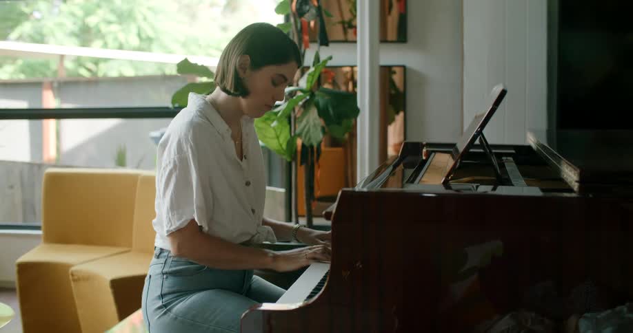 A woman plays a piano indoors during the day