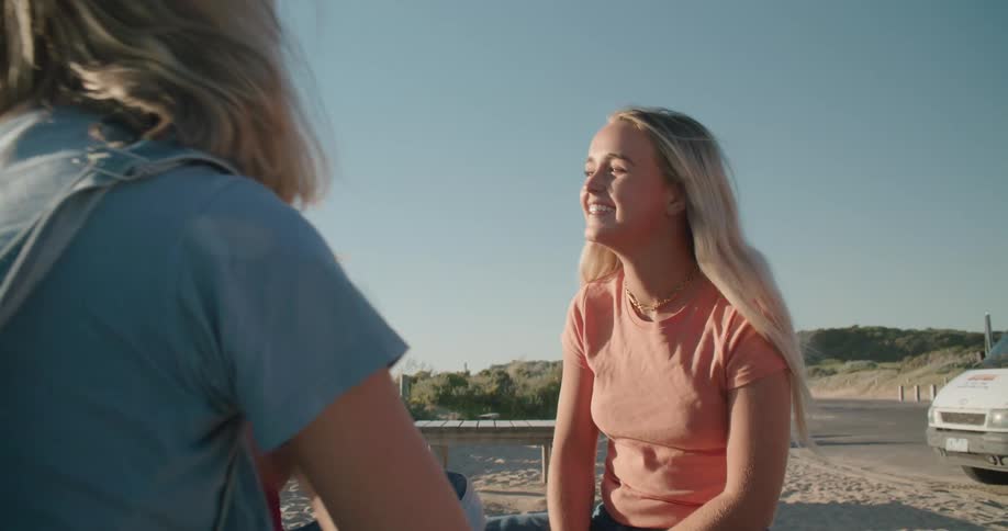 Three women are talking together while sitting in the sand