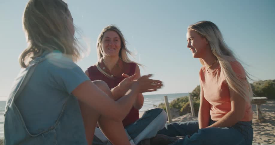 Three friends are laughing outdoors at the beach