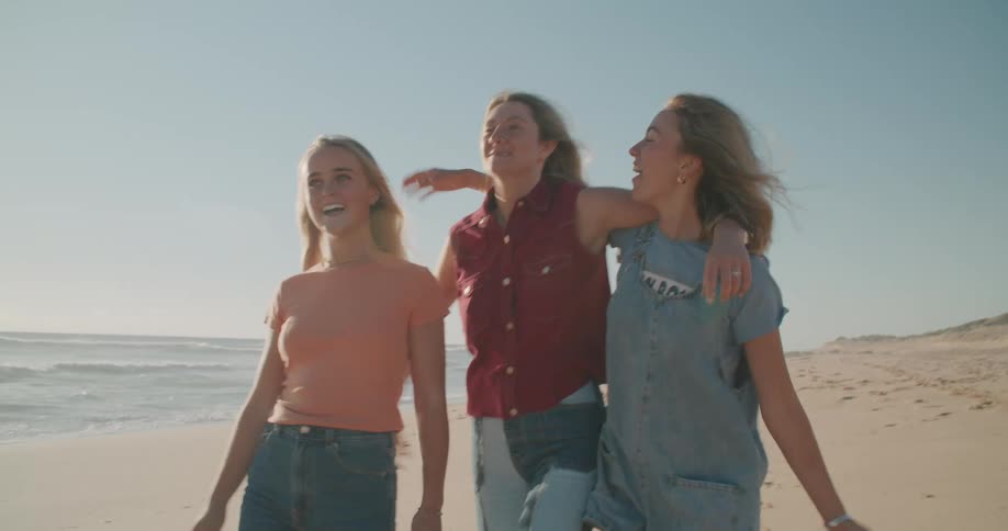 Three women are walking at the beach during the day