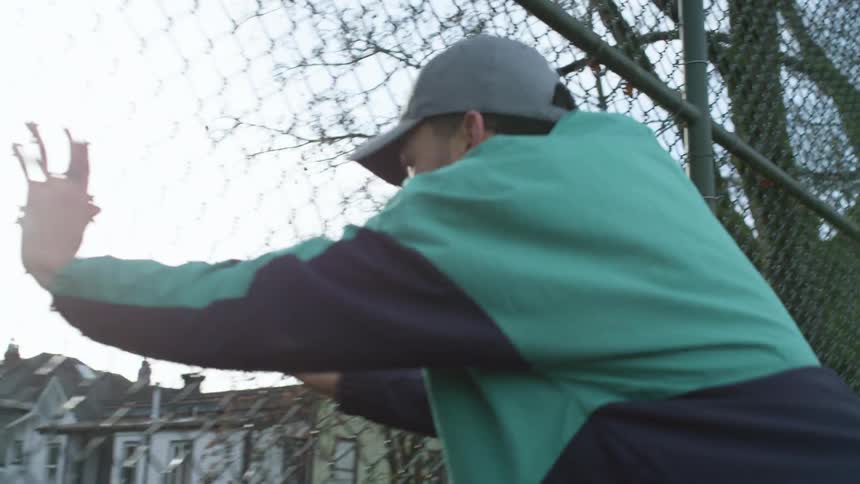 A man sprinting towards a chain link fence while exercising outdoors
