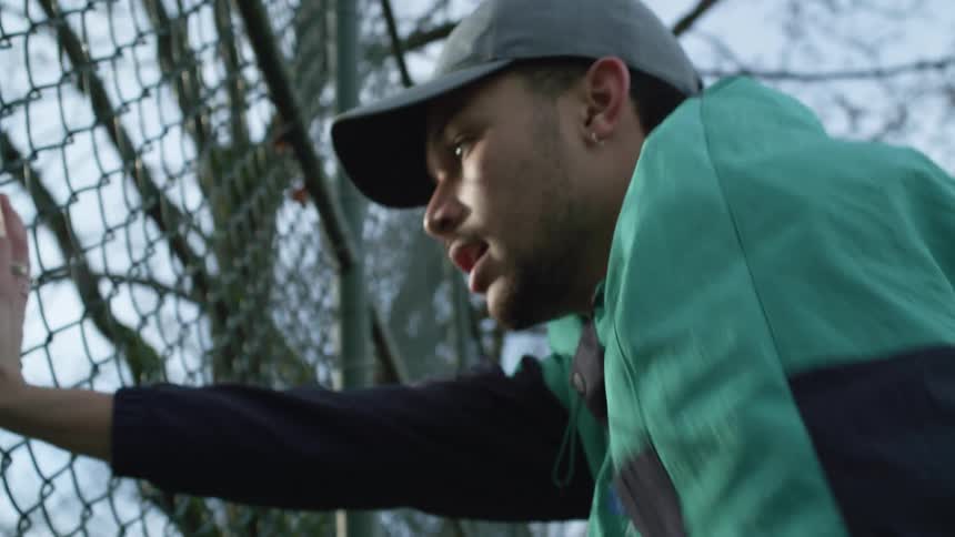 A man runs up to a fence and turns away