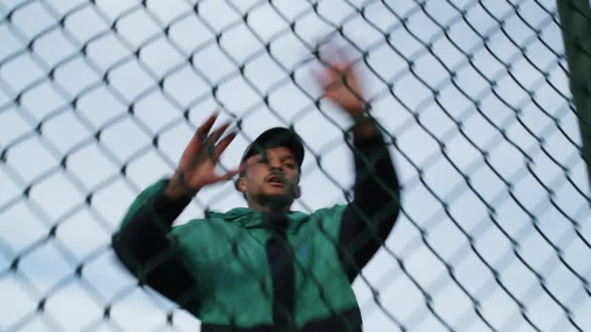 A man in a neighborhood runs and touches a fence and turns around and runs back