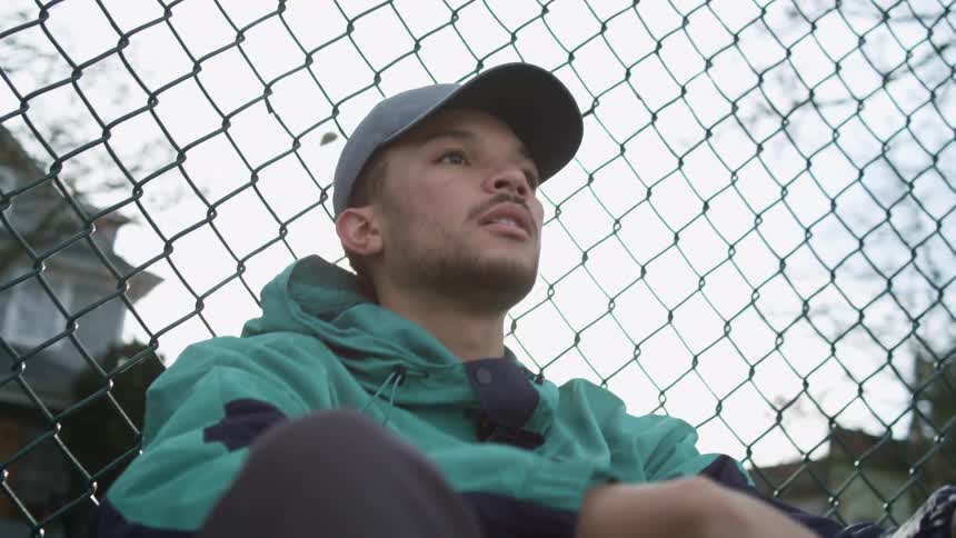 A man is sitting against the fence