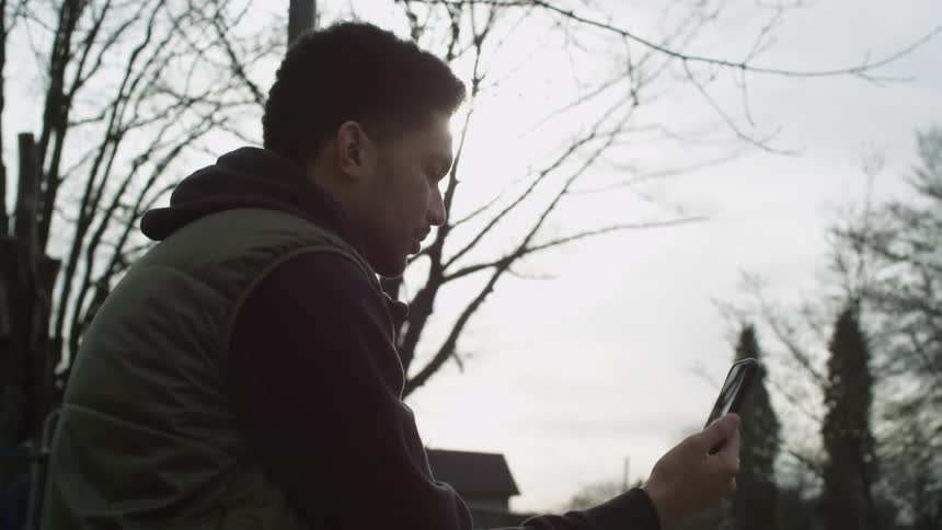 A man video chatting on a smartphone outside on a sunny fall day