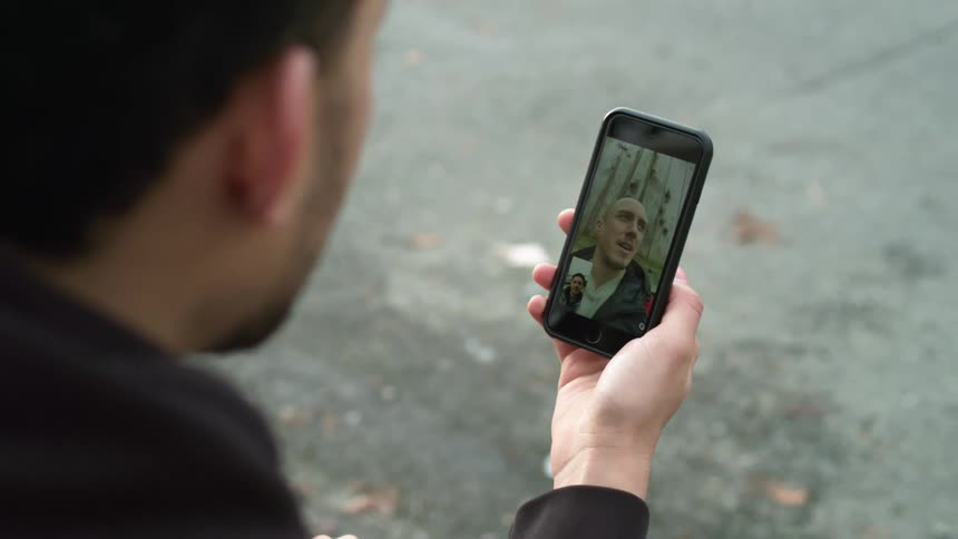 Man talking on a video call through a smartphone in the street at daytime