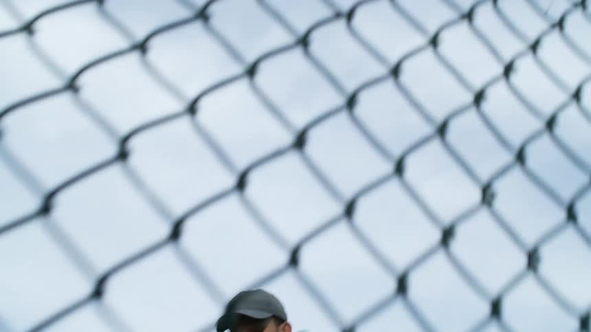 A man in a neighborhood runs and touches a fence and turns around and runs back