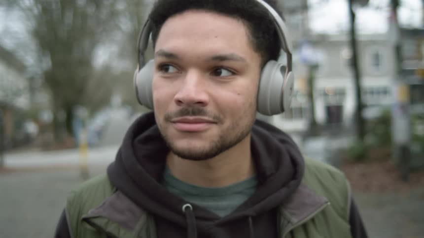 A man puts on headphones as he is walking