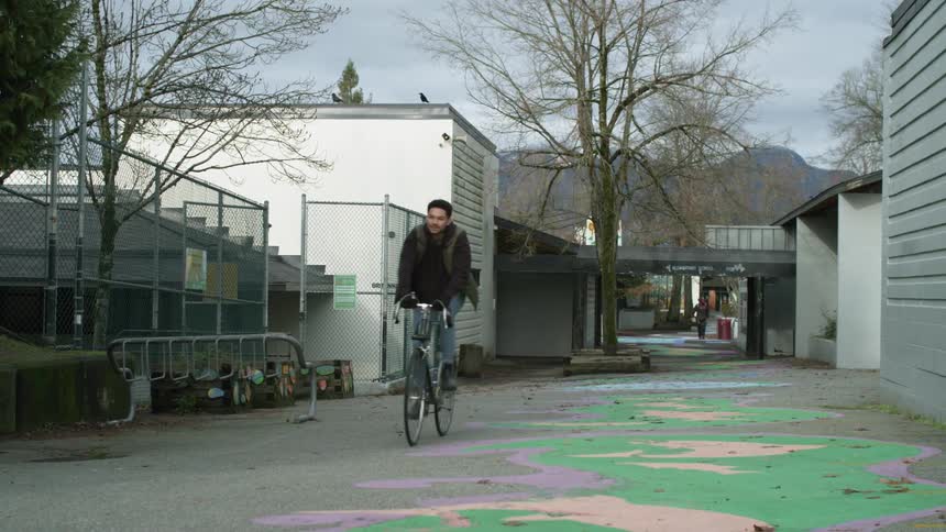 A man riding a bicycle next to buildings in a town