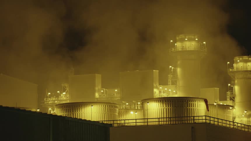 An exterior of an industrial area at night with smoke and lights