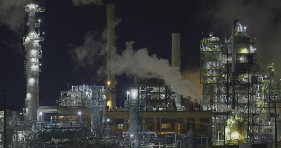 Oil refinery with lights chimneys and smoke with the sky in the background