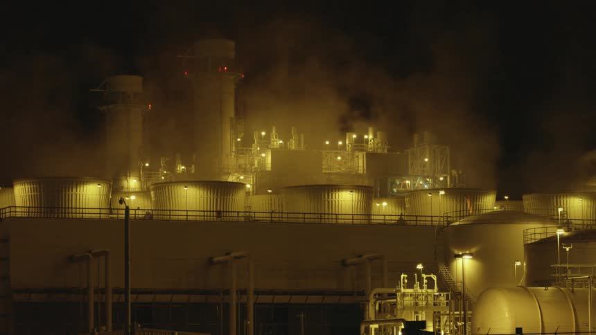The exterior of a white industrial park at night with smoke in the air