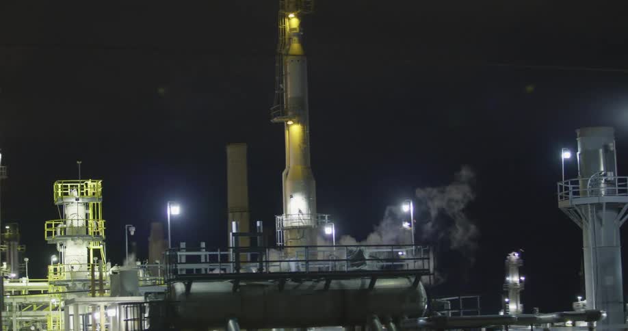 Towers and smokestacks in a refinery at night