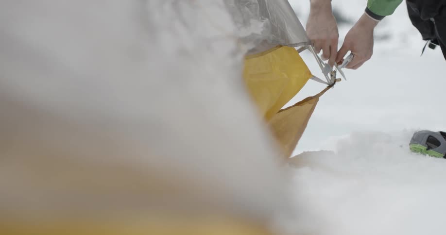 A man works at putting up a tent in the snow