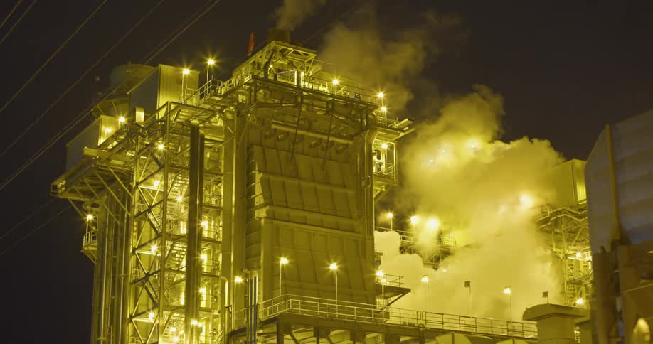 A view of a power plant that has smoke coming off of it