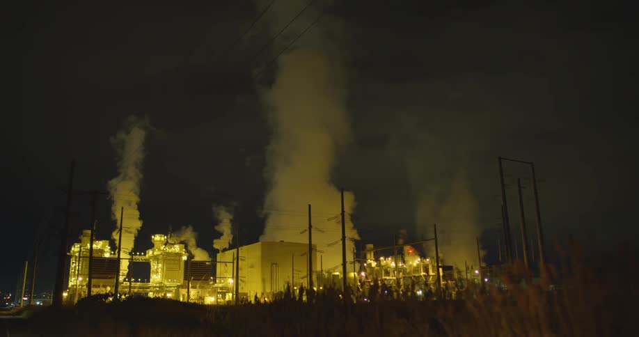 Pollution rising from a factory building at night