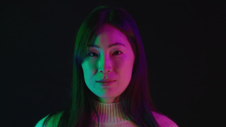 A young woman standing under a purple light
