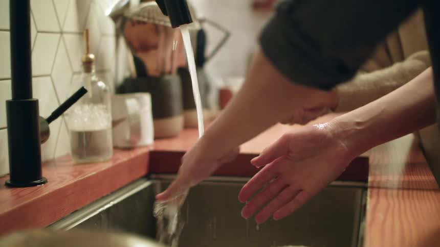 Two people washing hands in a kitchen sink