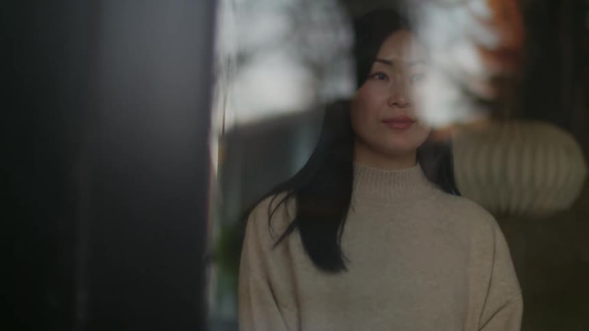 Morning light reflecting on the face of a woman looking out of the window