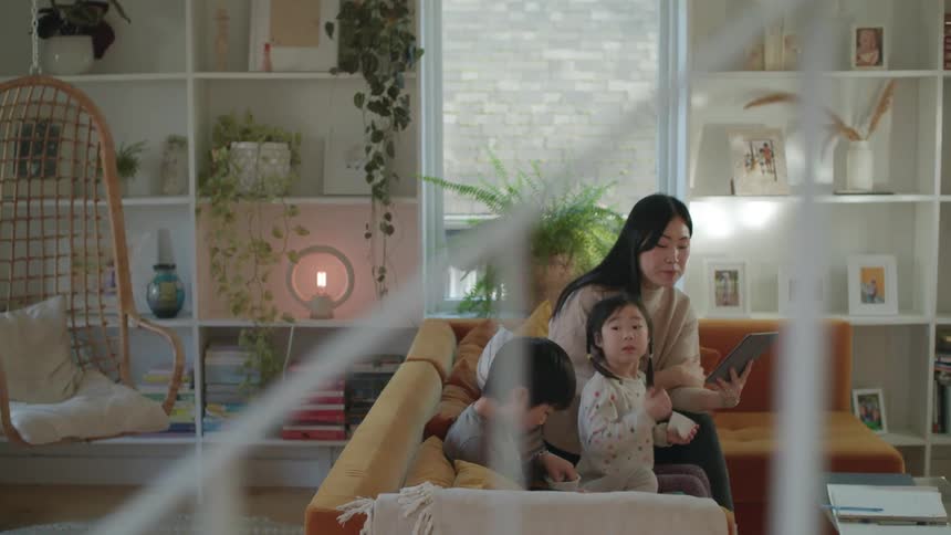 A mother sitting with her kids on a couch using a tablet