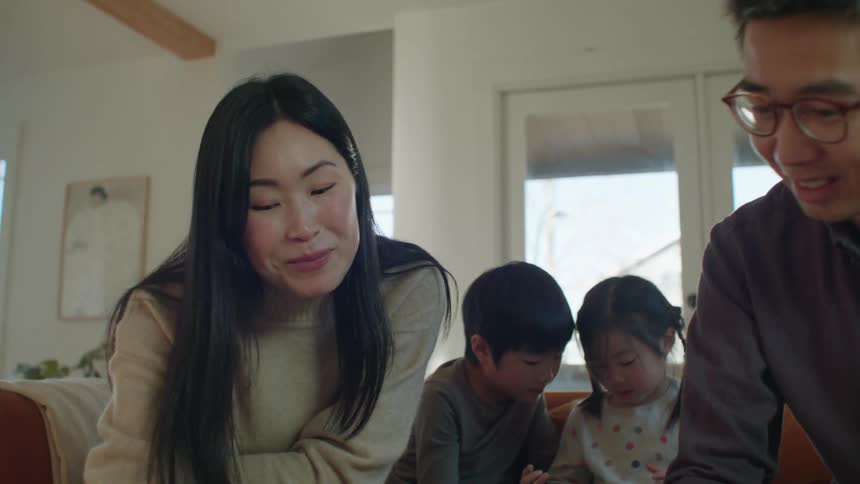 A young asian family talking and sitting on a living room couch