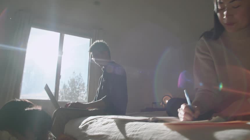 A young family hanging out in a bedroom on a sunny day