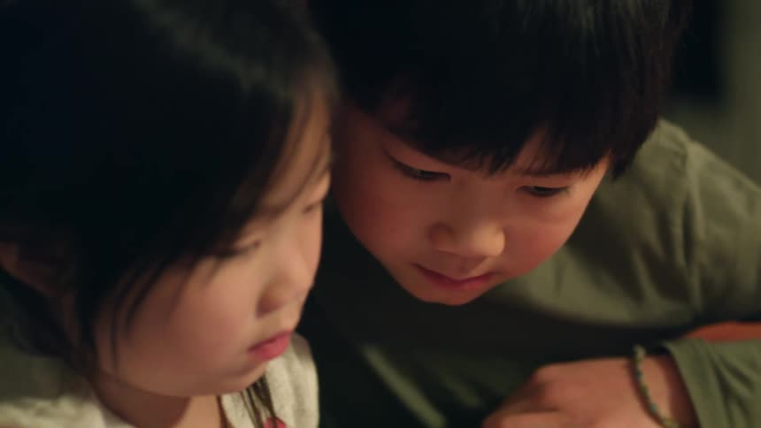 Two young siblings sitting next to each other indoors
