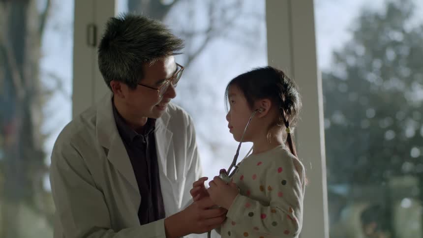 A doctor helping a young child listen to their own heart with a stethoscope