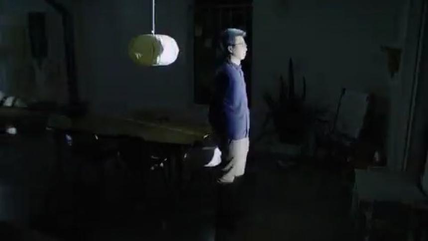 A man standing in a room with lights flashing with a table and chairs in the background