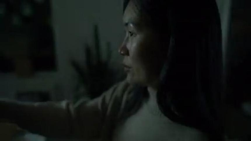 Lights flashing around a woman sitting in a dark house