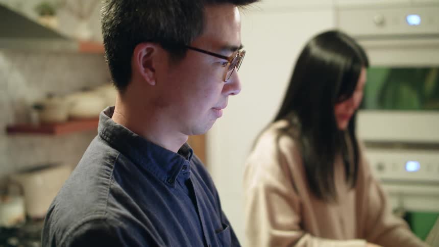 A man and woman talking while making dinner in a home kitchen