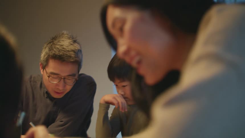 A family sit at the table coloring and writing