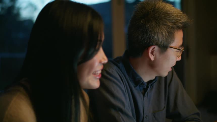 A man and woman smiling and laughing while looking at a laptop