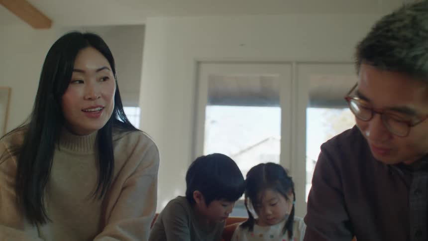 A young asian family talking while sitting on a living room sofa