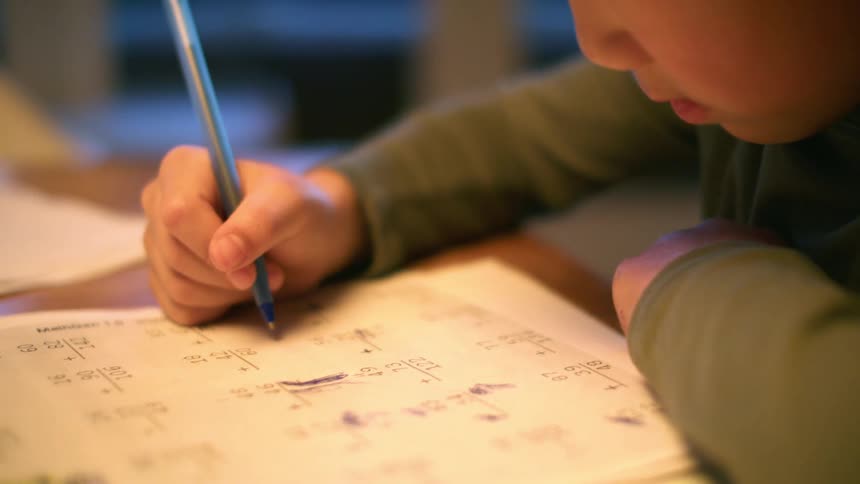 A young boy sits and does math homework
