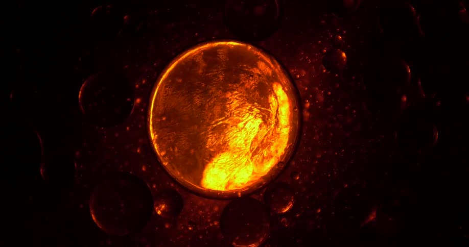 A yellow light shines through a translucent gel that forms large and small viscous bubbles