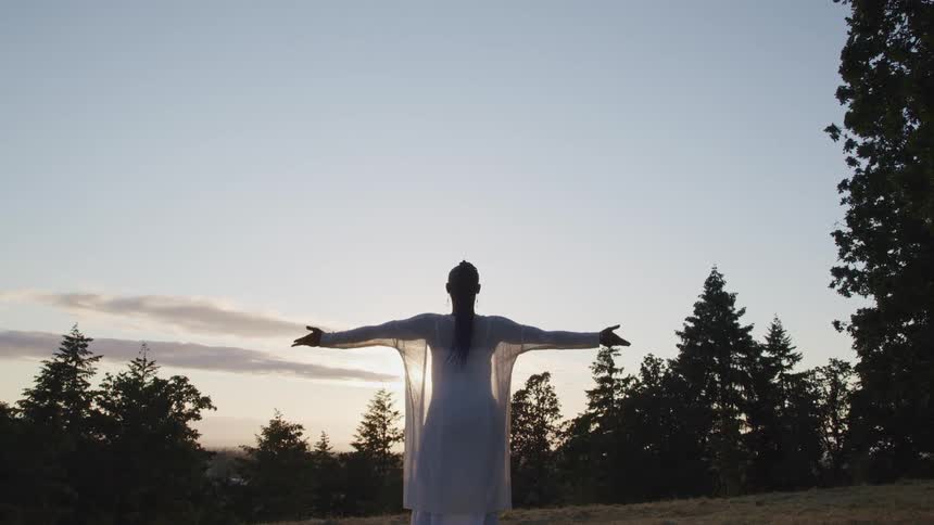 A woman stretching in a field in a dress