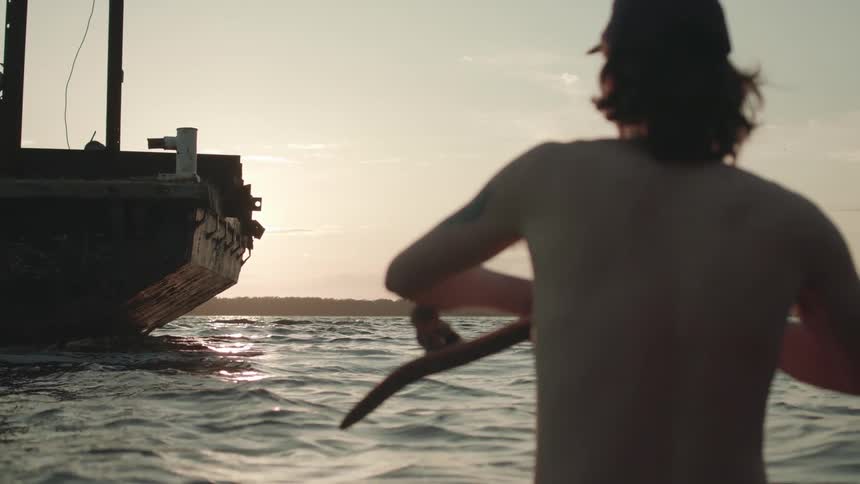 A man is standing outdoors near the ocean at dusk