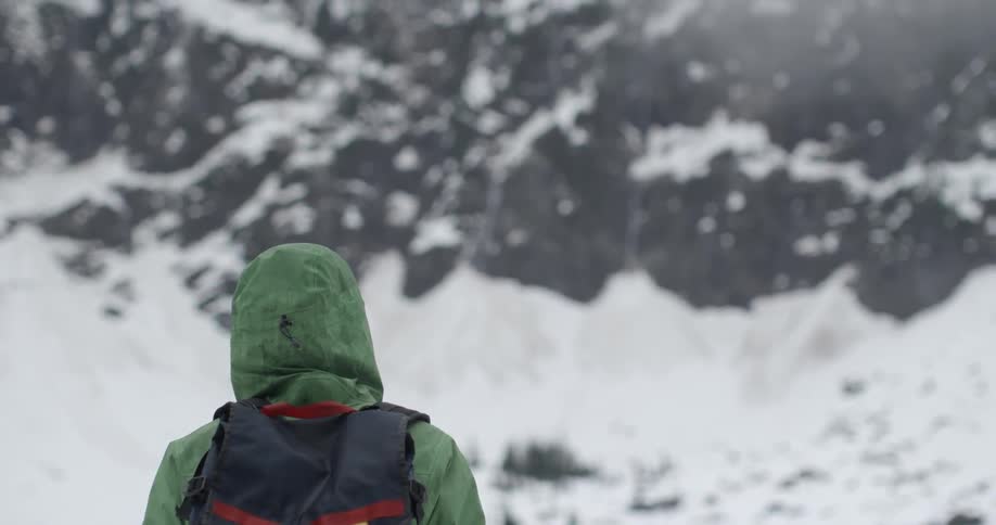 A hiker stands in the snowy mountains